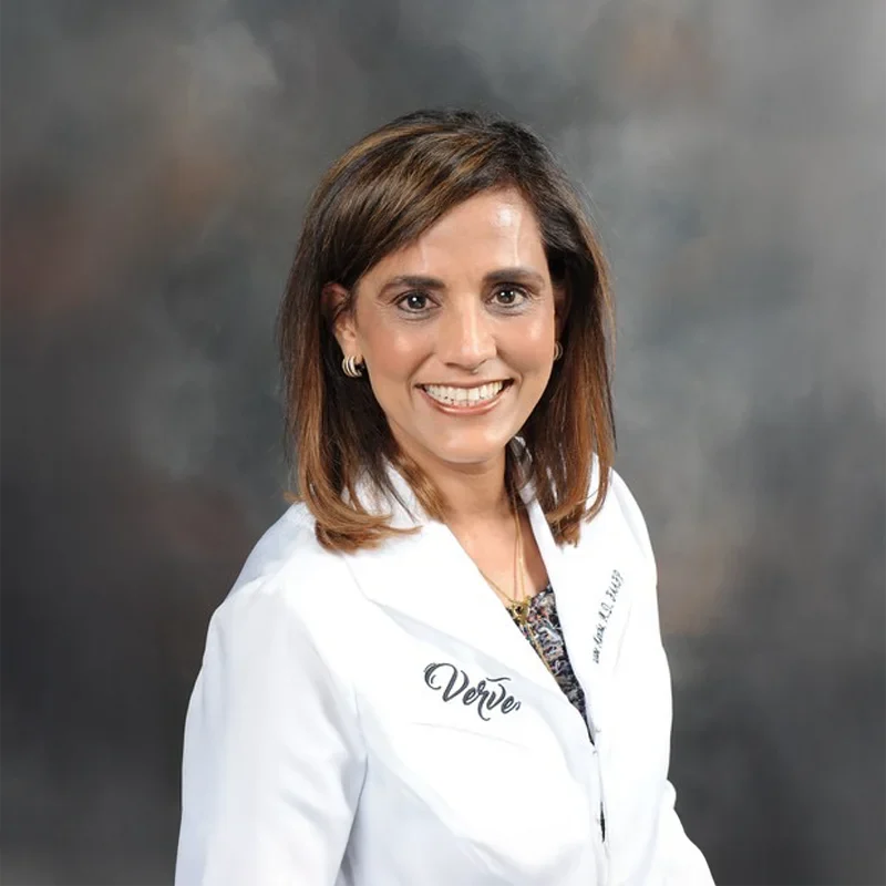 Dr. Usha Mantha posing for a professional photoshoot while wearing a white lab coat
